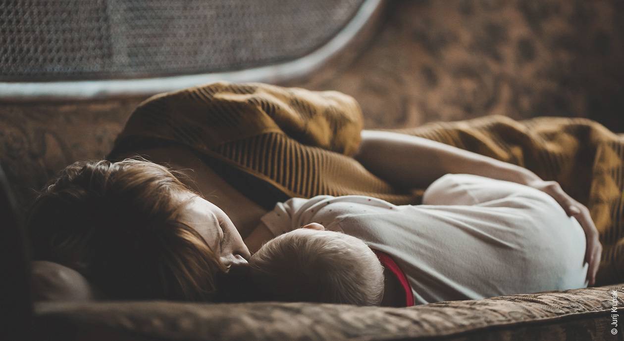 Foto: Mutter und Kind liegen beieinandergekuschelt im Bett.