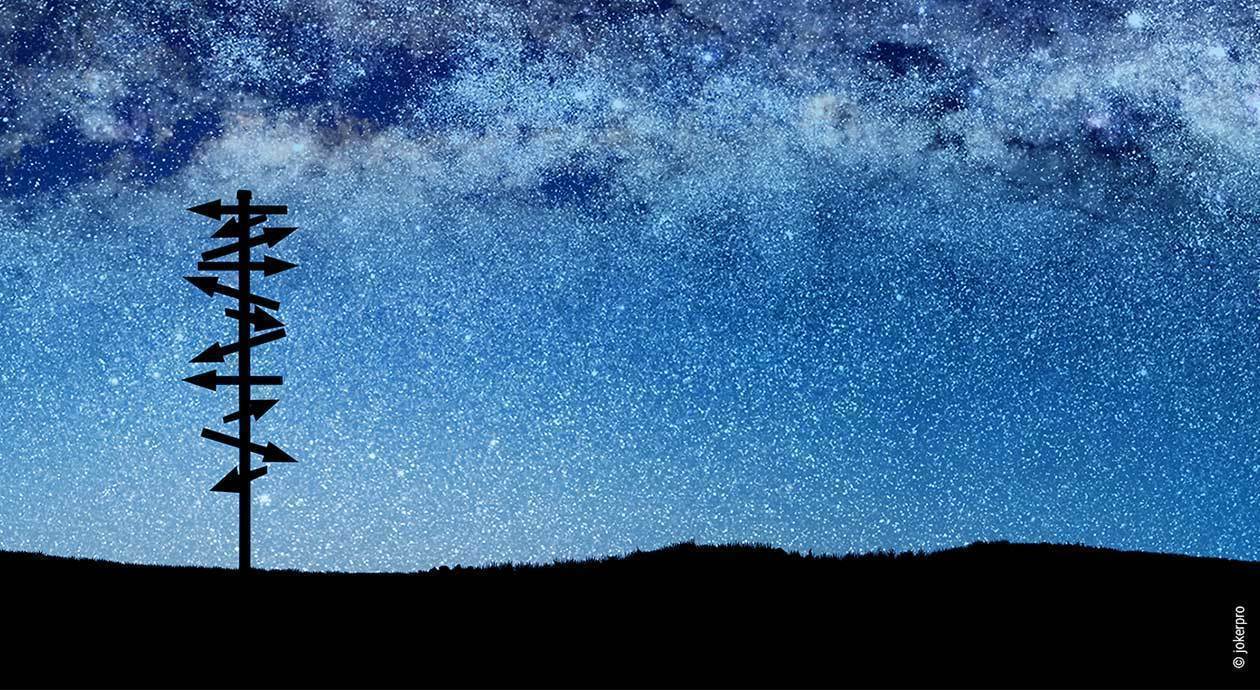 Foto: Ein sternenübersäter Nachthimmel, davor ein Wegweiser, dessen Pfeile in alle möglichen Richtungen weisen.