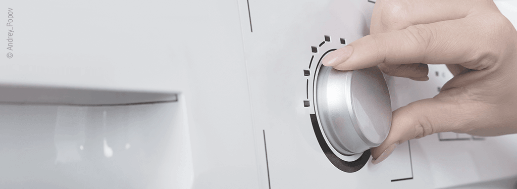 "Foto: Eine Hand am Programmknopf einer Waschmaschine