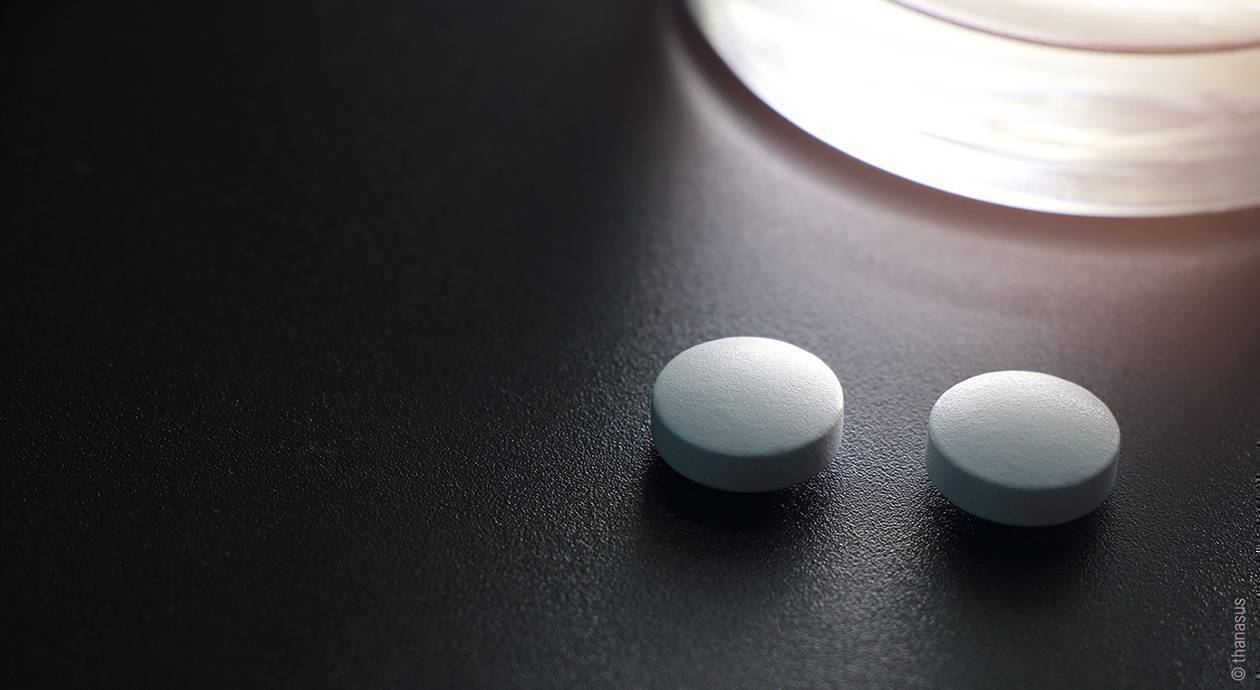 Foto: zwei runde, helle Tabletten auf einer dunklen Oberfläche