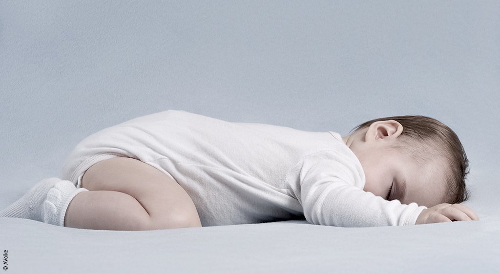 Foto: Ein Säugling in Bauchlage auf einer weichen Matratze.