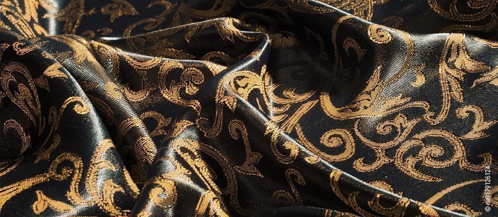 Foto: Eine schwarze Sommerbettwäsche aus Damast. Goldfarbene Muster sind in die Bettwäsche eingearbeitet.