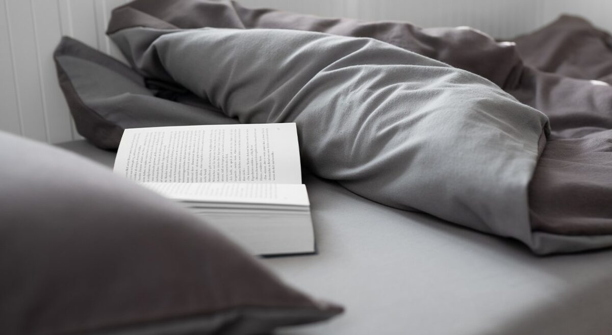 Foto: Auf einer Matratze liegt ein Kissen und eine Bettdecke, die zurückgeschlagen ist. Ein Buch liegt auf der Matratze.