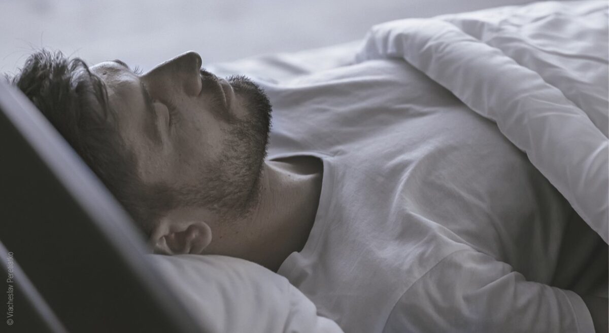 Foto: Ein Mann liegt im Bett und schläft; in diesem Beitrag geht es um Schlafhormone.