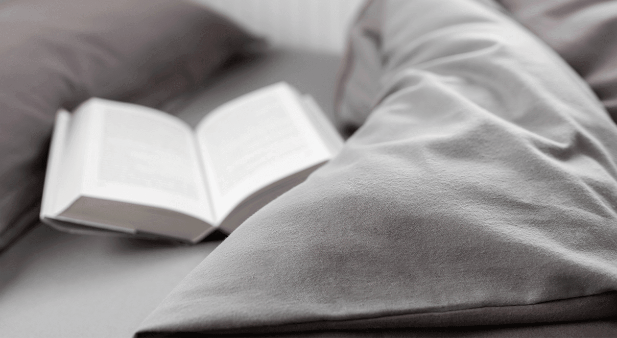 Foto: Ein Buch liegt aufgeschlagen auf einem Bett.