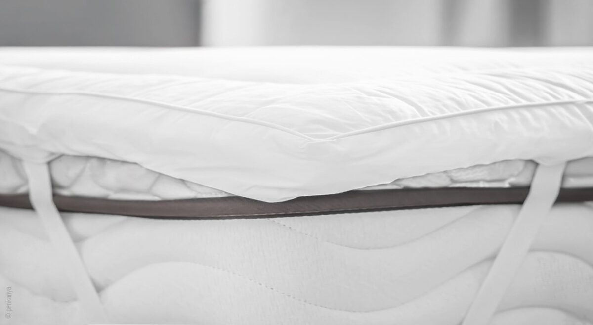 Foto: Ein weißes Unterbett ist an einer Matratze befestigt.
