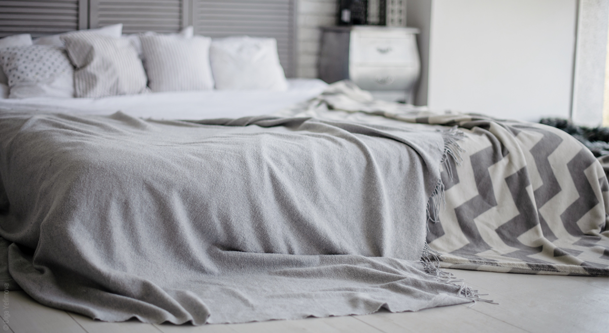 Titel: Frontansicht eines Bettes, auf dem ein Bettüberwurf zu sehen ist und weitere verschiedene Tagesdecken.