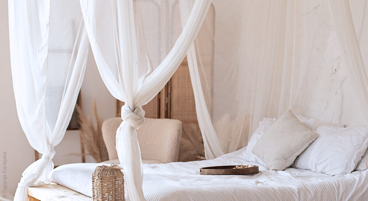 Foto: Ein Doppelbett mit Moskitonetz als Betthimmel. Der Insektenschutz ist an den vier Ecken des Bettes jeweils zusammengebunden.
