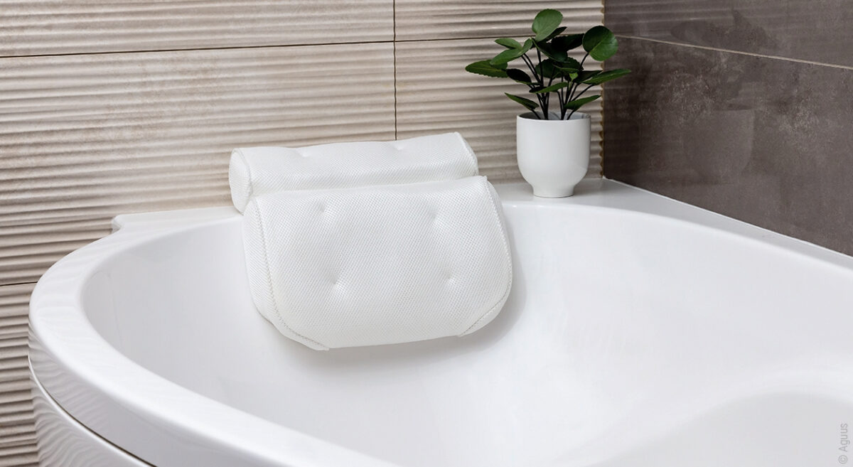 Foto: Ein Badekissen ist am Kopfende einer Badewanne angebracht. Daneben steht eine Pflanze