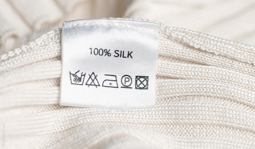 Foto: Ein Waschzeichenetikett auf einem Textilstück, das 100% SILK und waschzeichen listet.