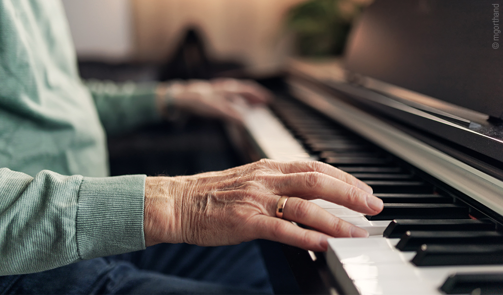 Foto: Zwei älter wirkende Hände spielen Klavier.