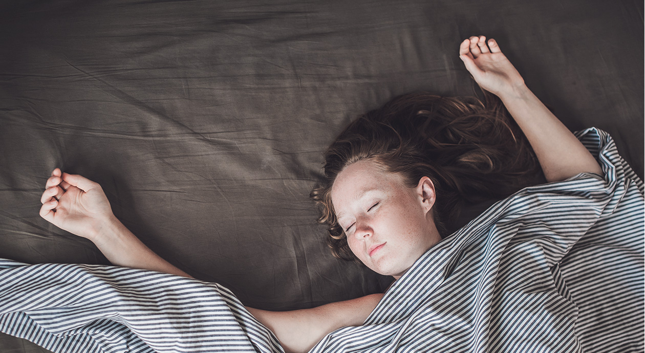 Titelbild ohne Kissen schlafen: eine Person liegt mit geschlossenen Augen ohne Kissen in Rückenlage im Bett.