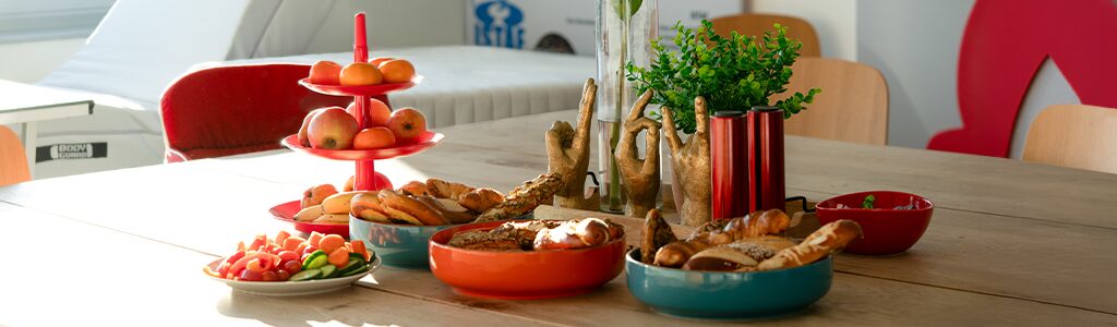 Foto: Auf einem großen Tisch stehen Obst, Gemüse und Teigwaren dekorativ in Schüsseln und einer Etagere angerichtet.