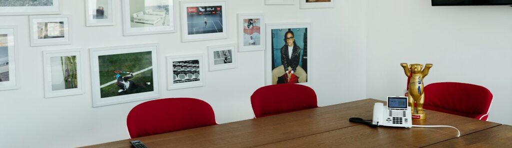 Foto: In einem Meetingraum hängen Bilder an der Wand, auf dem Tisch ein Telefon und eine Bärenfigur.