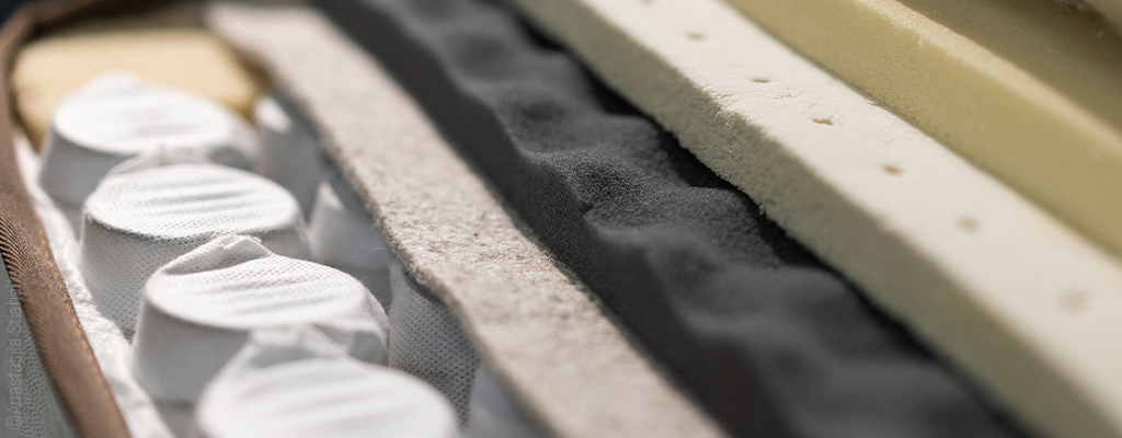 Das Innere einer Taschenfederkernmatratze. Auf den in Stofftaschen eingenähten Federn liegen mehrere Schichten aus Schaum.